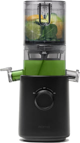 A black and clear NAMA slow masticating juicer filled with green juice, oranges, and leafy greens, shown on a solid white background.