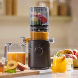 NAMA J3 cold press juicer with fresh fruits and juice on a kitchen counter.