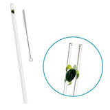 Clear glass straw with green turtle charm and cleaning brush on a white background